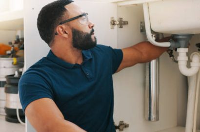 Plumber black man, kitchen and sink maintenance with tools, focus and pipe repair for drainage in home. Entrepreneur handyman, plumbing expert or small business owner in house for fixing water system