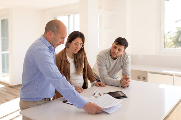 Argentinean real estate agent and young happy heterosexual couple signing contract for their new home - Buenos Aires - Argentina